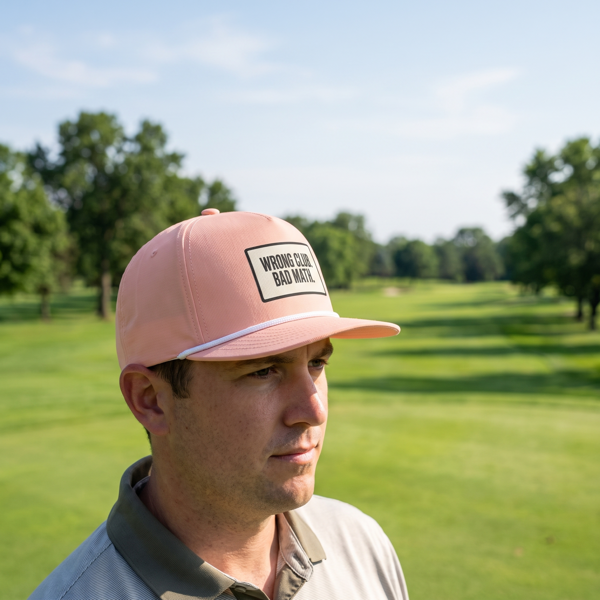 A golfer on a golf course wearing the Wrong Club. Bad Math. rope hat in Peachy with a white rope.