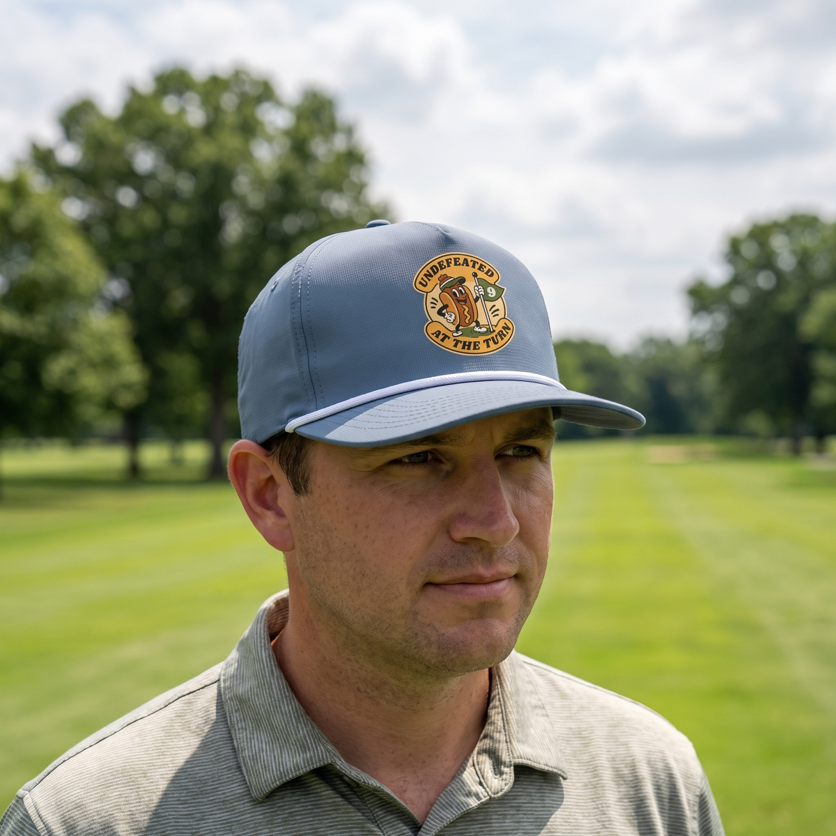 A golfer on a golf course wearing the Undefeated at the Turn rope hat in Blue Jean with a white rope.