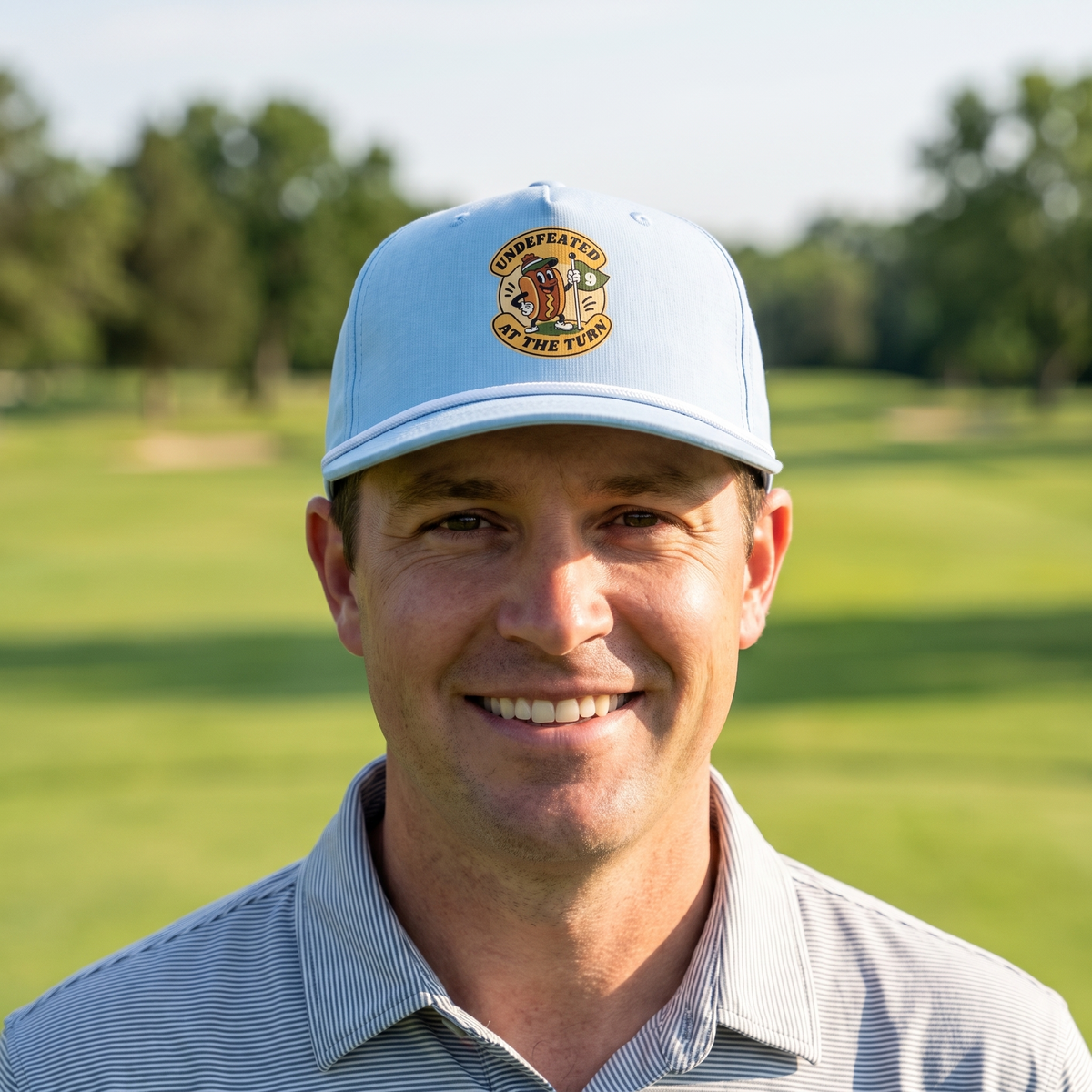 A golfer on a golf course wearing the Undefeated at the Turn rope hat in Chambray with a white rope.