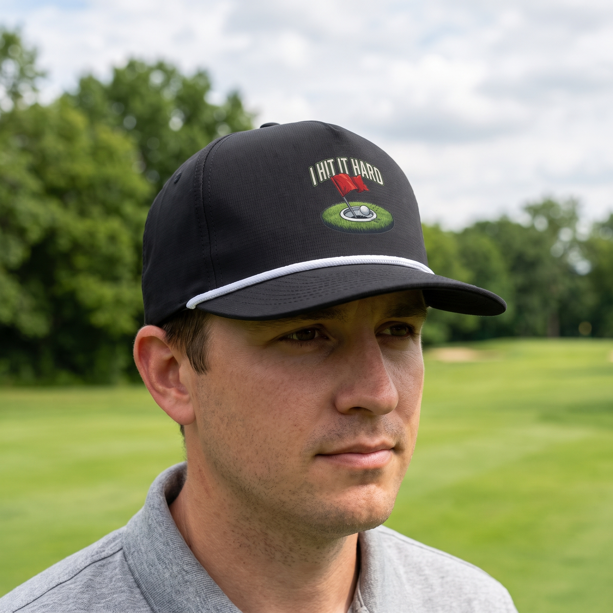 A golfer on a golf course wearing the I Hit It Hard rope hat in Black with a white rope.