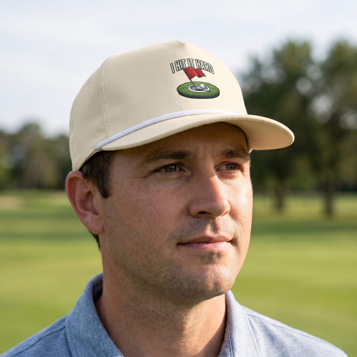 A golfer on a golf course wearing the I Hit It Hard rope hat in Ivory with a white rope.