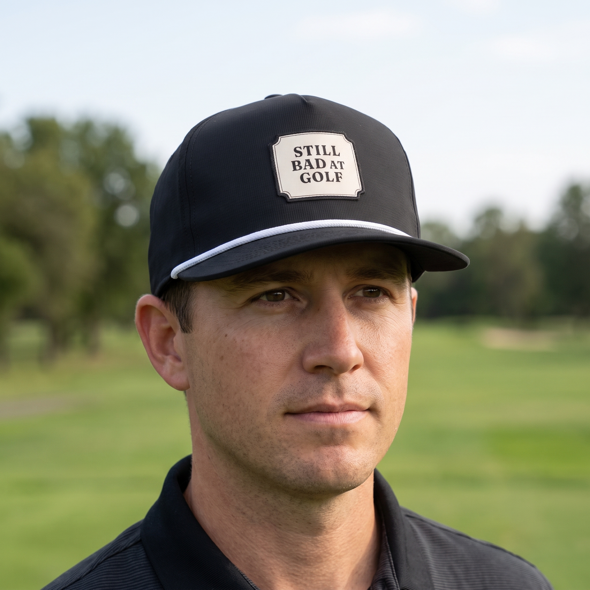 A golfer on a golf course wearing the Still Bad at Golf rope hat in Black with a white rope.
