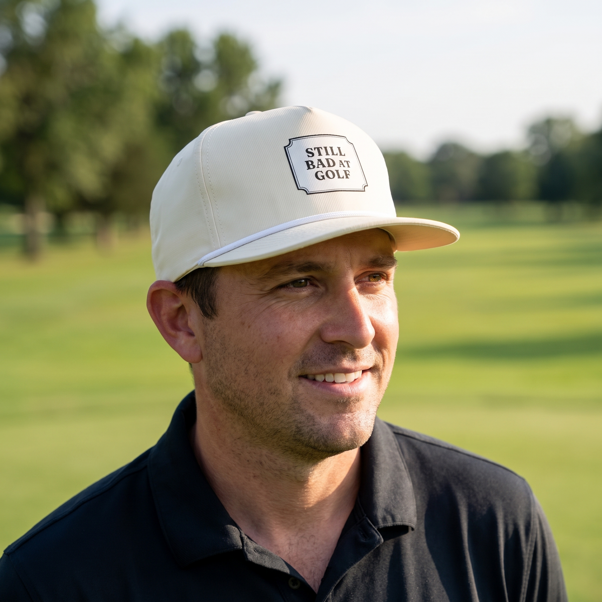A golfer on a golf course wearing the Still Bad at Golf rope hat in Ivory with a white rope.