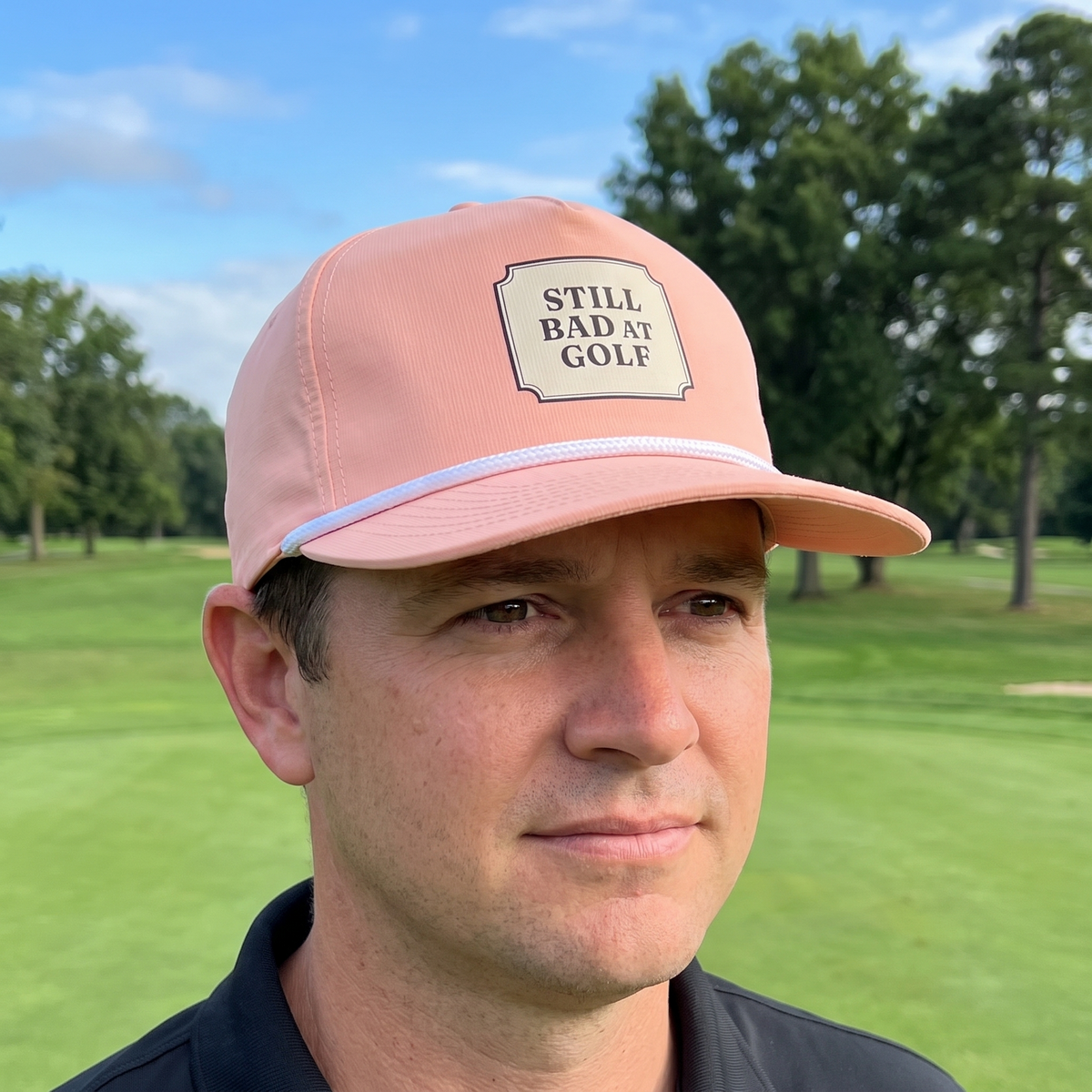 A golfer on a golf course wearing the Still Bad at Golf rope hat in Peachy with a white rope.